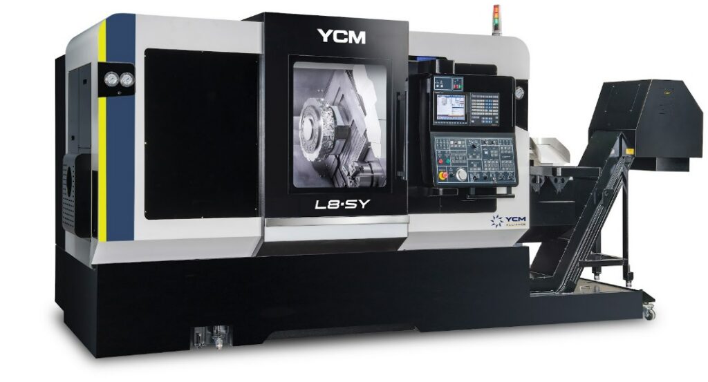 A large gray and black CNC machine features a large window to view inside the machine, a keyboard, and a conveyor.
