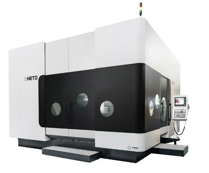 A very large black-and-white industrial machine features several small holes and a small computer on the side.